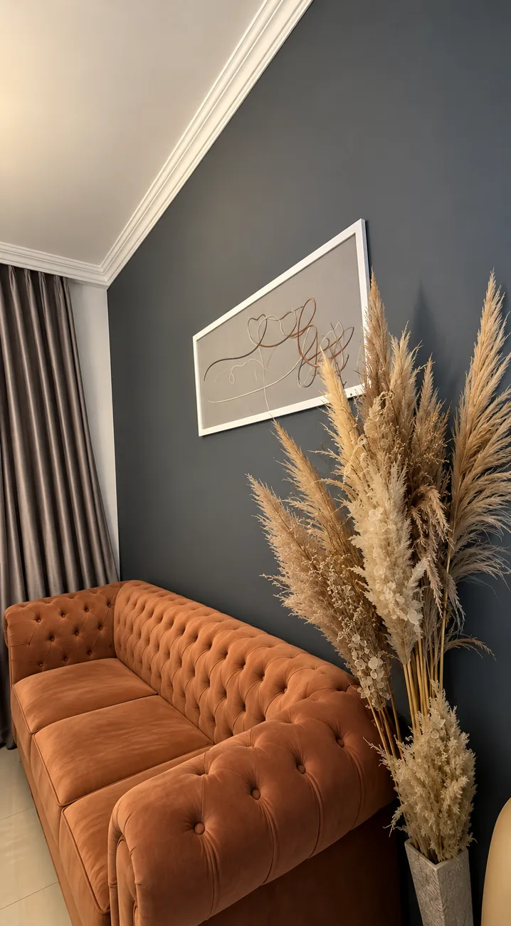 Sala de espera do estúdio com sofá de veludo, capim dos pampas e o quadro da Greice Allmeida